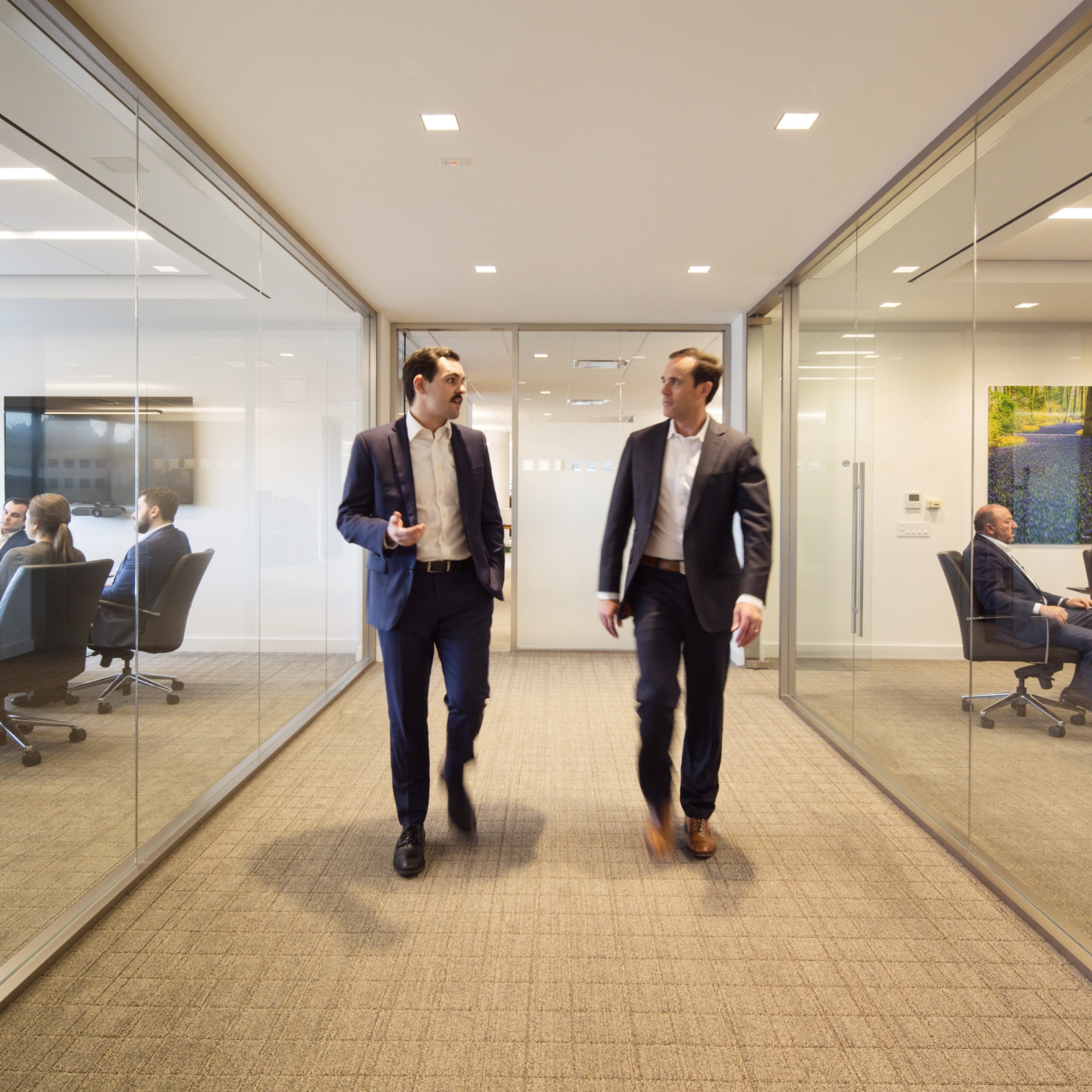 Two businessmen walking in modern office corridor.