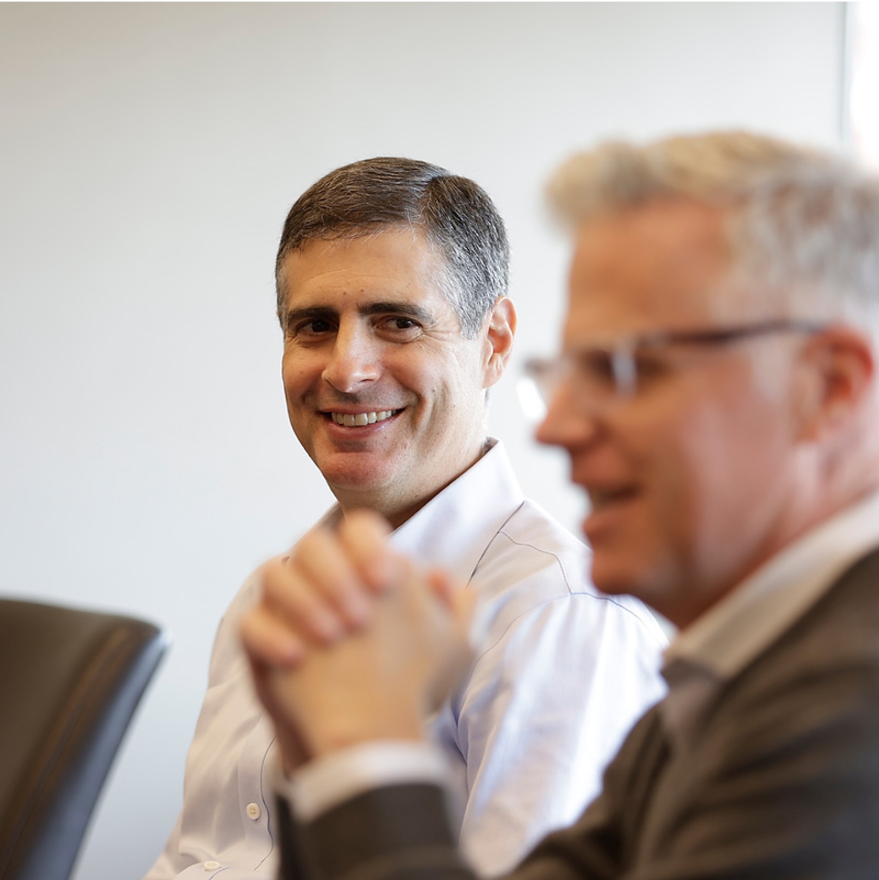 Two men smiling during a meeting discussion.